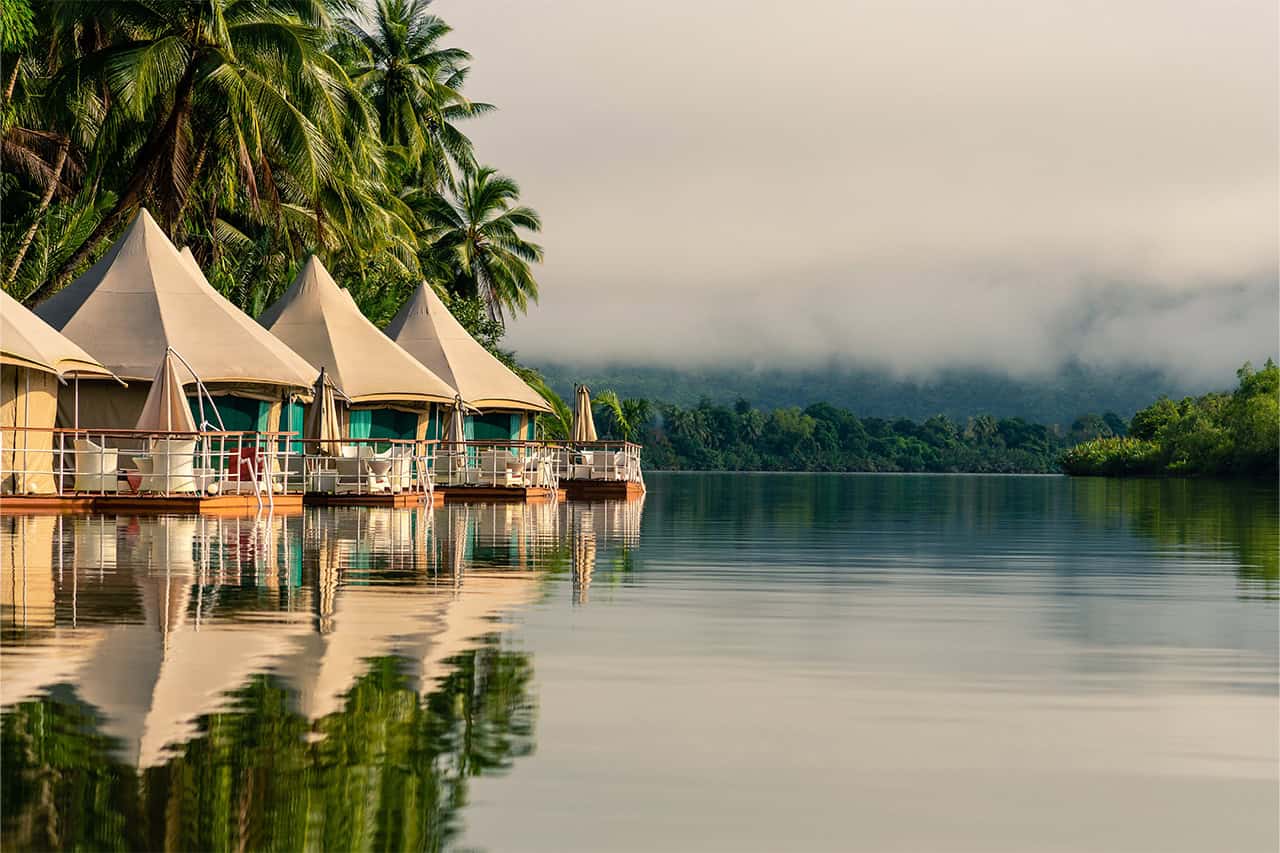 Luxury floating tents at Canvas and Orchids Retreat on the Tatai River, Cambodia, surrounded by lush tropical jungle.